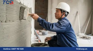 Một người thợ đang dùng chổi sơn lớn quét lớp hồ dầu xi măng lên tường